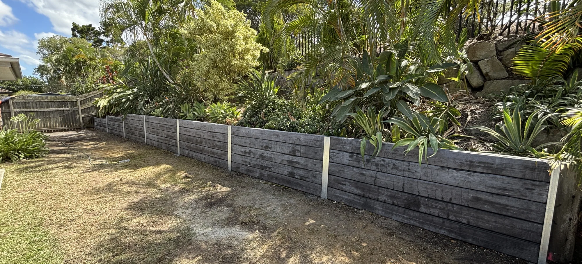 Timber-look concrete sleeper retaining wall around a garden