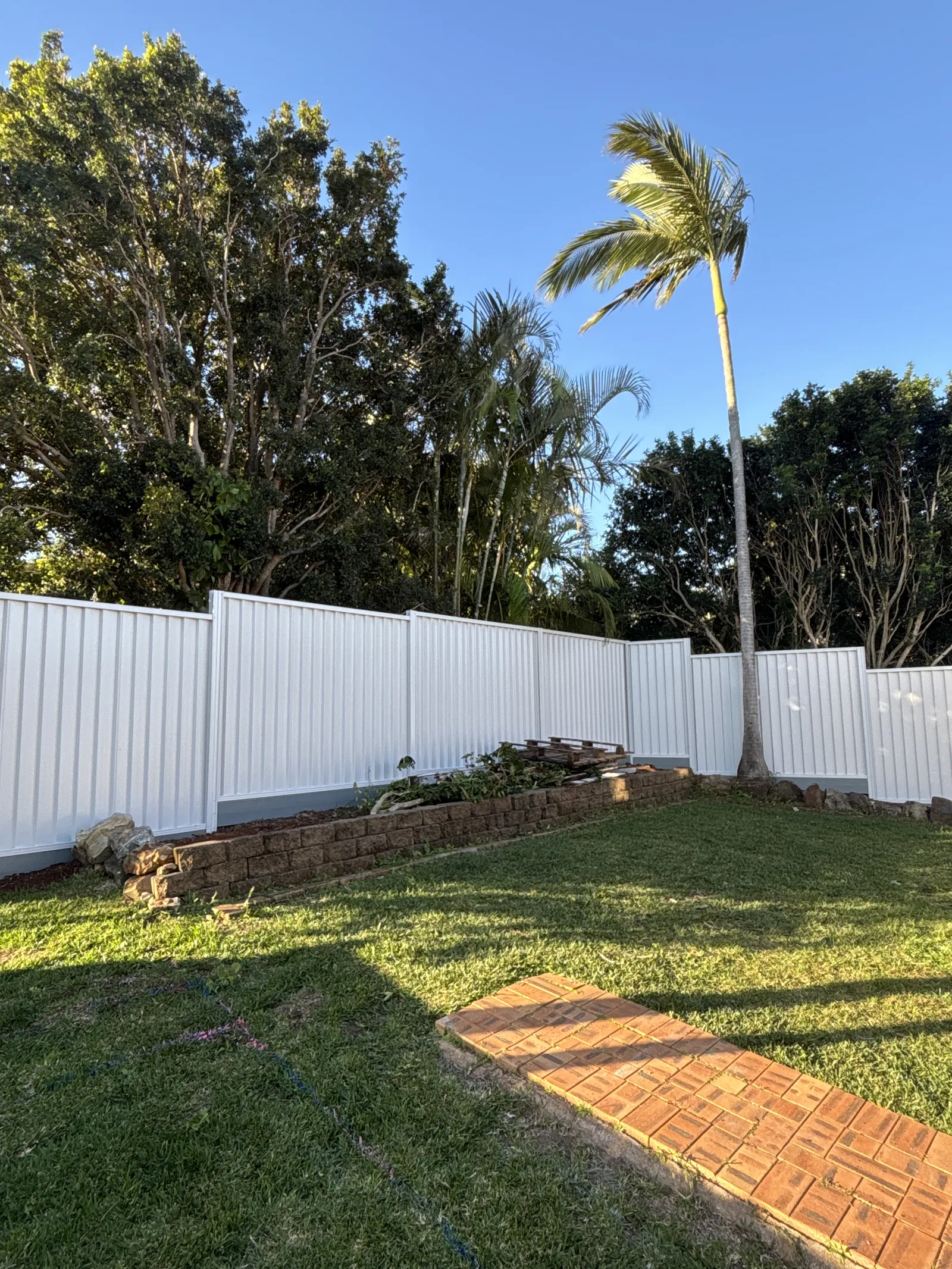 White Colorbond fence, lawn and brick path