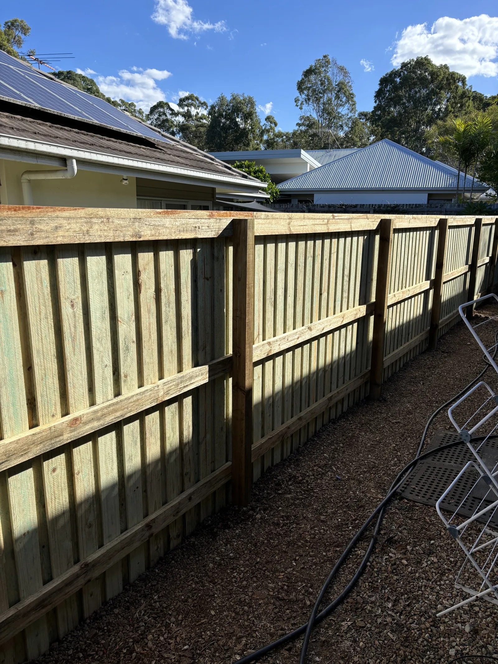 Back of a paling fence showing three rails and posts