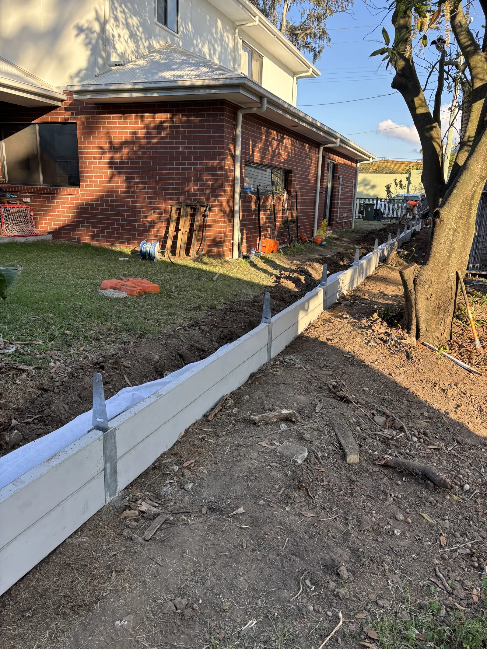 Low concrete sleeper retaining wall along a house boundary
