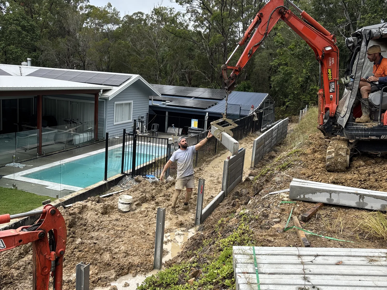 Retaining wall being built beside a pool with a mini excavator