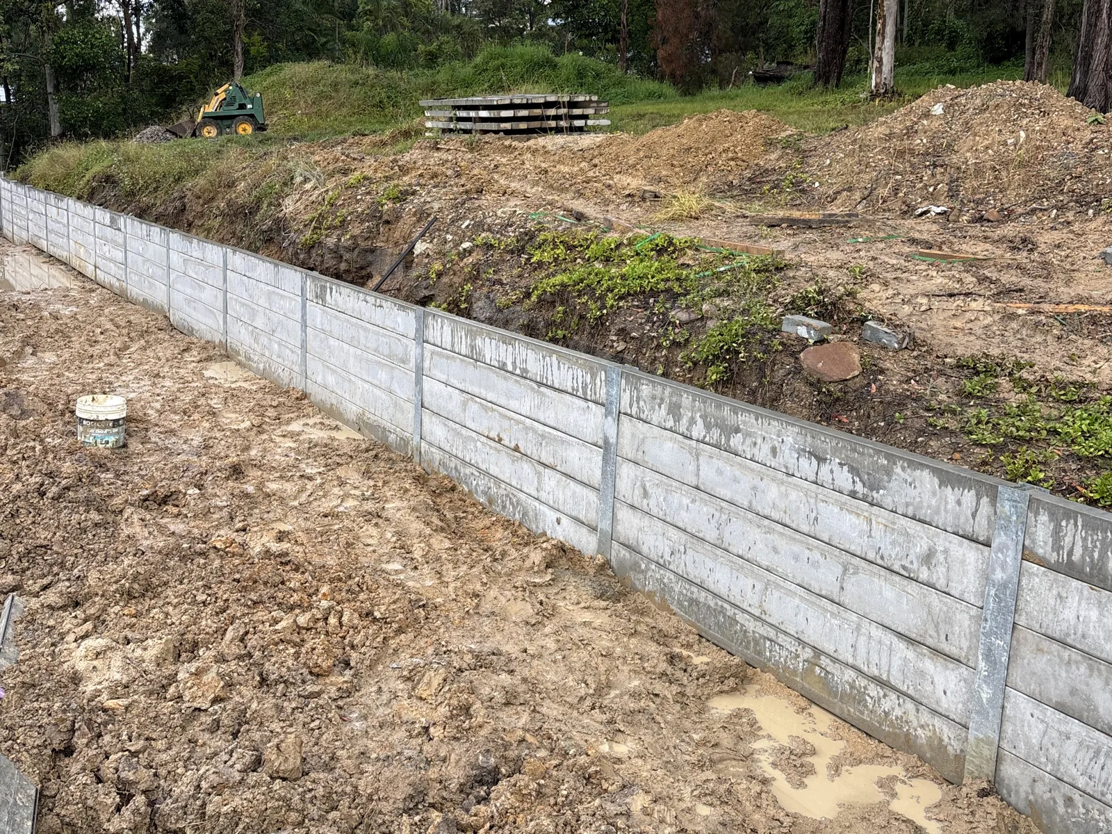 Long concrete sleeper retaining wall with galvanised steel posts on a cut slope